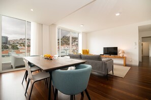 Een moderne woonkamer met een eethoek, grote ramen en uitzicht op de stad.