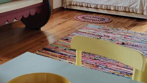 A bedroom with a bed, a sofa, a chair, a table, and two paintings on the wall. - Casa do Cachorro – Adega Chamarrita (Madalena (Açores))