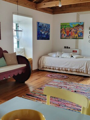 Ein Schlafzimmer mit einem Bett, einem Sofa, einem Sessel, einem Tisch und zwei Bildern an der Wand.