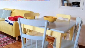 A dining area with a wooden ceiling, a painting on the wall, and a yellow sofa. - Casa do Cachorro – Adega Chamarrita (Madalena (Açores))