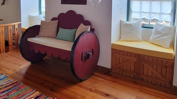 A room with a wooden ceiling, a swing seat, a hanging light fixture, and a window with a view. - Casa do Cachorro – Adega Chamarrita (Madalena (Açores))