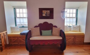 A cozy room with a cushioned bench, a decorative wall hanging, and a hanging light fixture.
