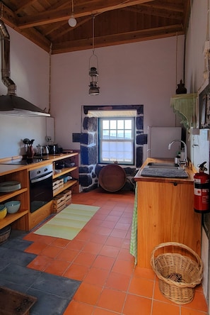 Eine Küche mit Steinwand, Holzschränken, einem Herd und einem Fenster.