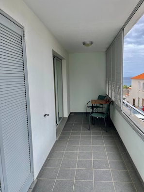 Ein Balkon mit Tisch und Stühlen, einer Schiebetür und Blick auf das Meer.