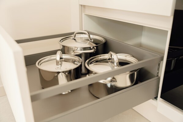 A kitchen drawer with stainless steel pots.