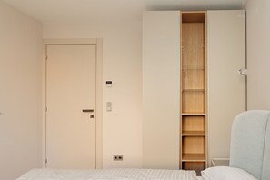 Un dormitorio con cama, armario y estantería empotrada.