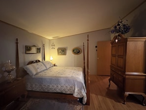 Quarto com cama de dossel, cómoda de madeira e obra de arte na parede.