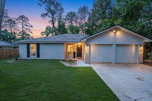 Ein einstöckiges Haus mit Veranda, Garage und gepflegtem Rasen.