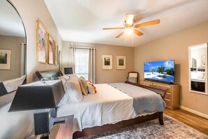 Ein Schlafzimmer mit einem Bett, einem Fernseher, einem Deckenventilator und gerahmten Bildern an der Wand.