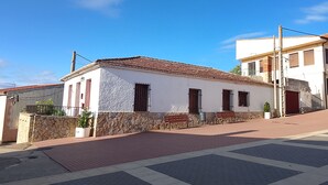Un bâtiment à deux étages, doté d’un toit en tuiles, de fondations en pierre et d’une zone pavée devant l’entrée.