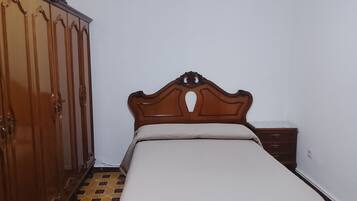 Ein Schlafzimmer mit einem hölzernen Bett, einem Kleiderschrank und einem Nachttisch.