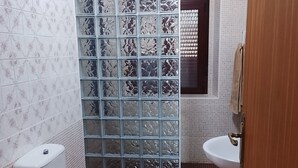 Une salle de bain comprenant des toilettes, un lavabo, un carrelage décoratif et une cloison en verre ornementale.