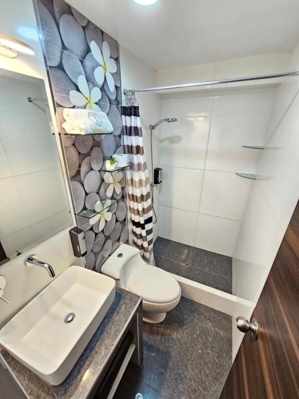 A bathroom with a white sink, toilet, and shower area.
