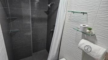 Een moderne badkamer met een douchecabine, een toilet en een handdoekrek met een opgerolde handdoek.