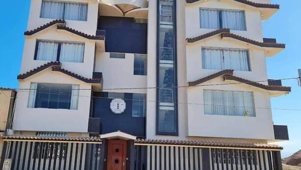 A multi-story building with a central vertical feature, balconies, and a gated entrance.