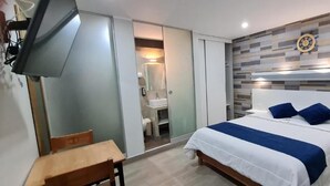 A modern bedroom with a bed, bedside tables, a desk, and a TV.