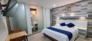 A modern bedroom with a bed, bedside tables, a desk, and a TV. - EL FARO HOTEL (Chala)