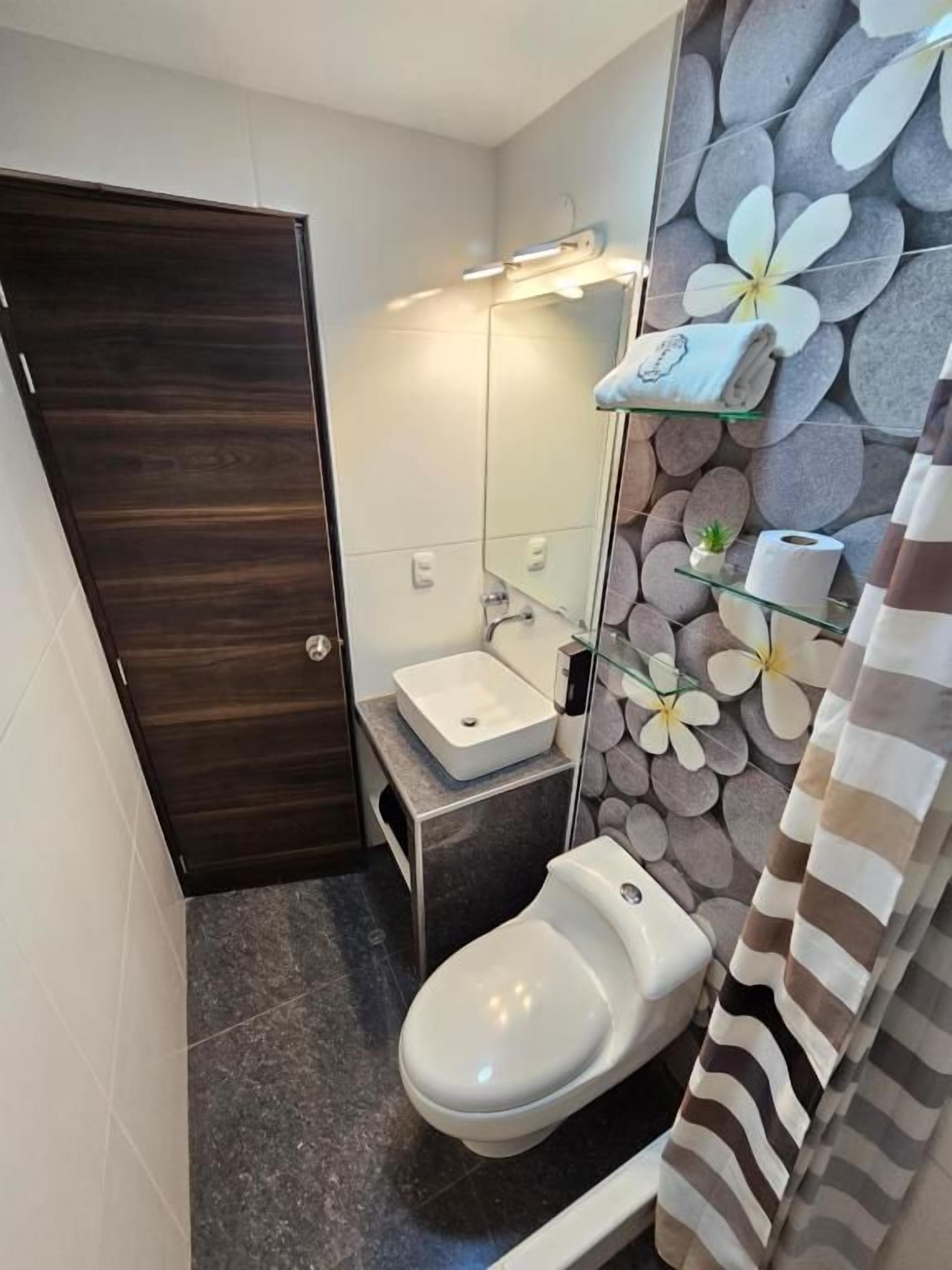 Un baño pequeño con inodoro, lavamanos y espejo.