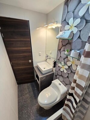 A compact bathroom with a toilet, sink, and a mirror.