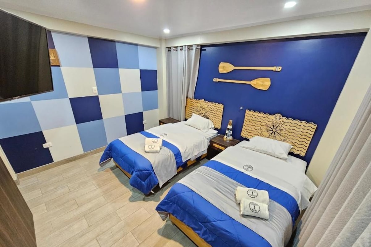 A hotel room with two beds, a checkered wall, and a wooden headboard with paddle designs.
