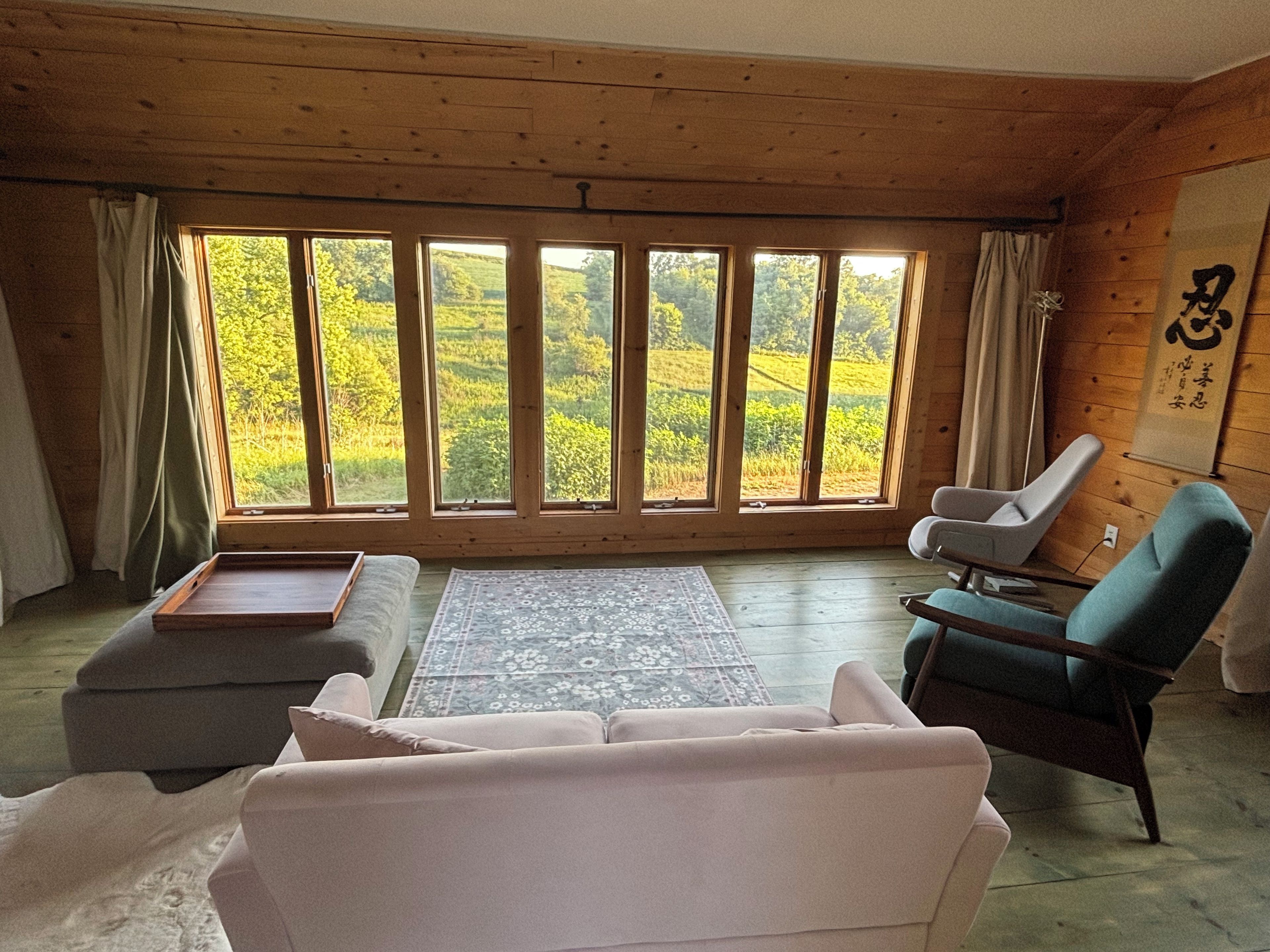 Une pièce avec une grande fenêtre, un canapé, un fauteuil et une petite table.