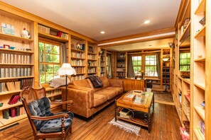 A cozy library with bookshelves, a sofa, a chair, and a coffee table.