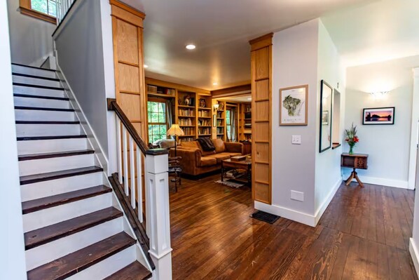 A staircase leading to a living area with a fireplace, bookshelves, and a sofa.
