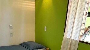 Une chambre d’hôtel avec deux lits, l’un recouvert d’une couvre-lit à rayures et l’autre d’une couverture unie. Il y a des serviettes blanches sur les lits.