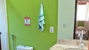 Une salle de bain avec un mur vert, des toilettes blanches, un lavabo avec un plan de travail en marbre et une serviette accrochée au mur.