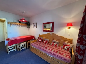 Ein Schlafzimmer mit einem Holzbett, einem roten Tisch und einer Bank.