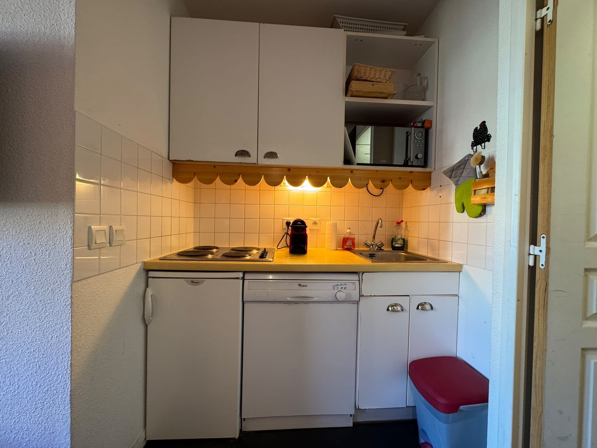 A compact kitchen with white cabinets, a microwave, a sink, and a dishwasher.