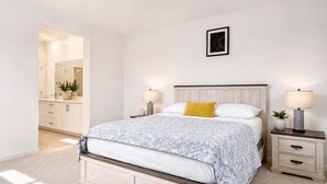 A bedroom with a bed, bedside tables, a nightstand, a mirror, and a wall-mounted picture. - Fully Furnished 3BR and 3BA Retreat with Views (Eastvale)