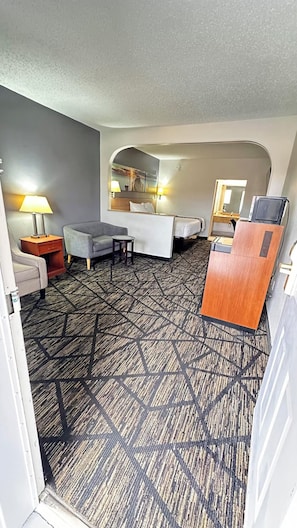 Ein Hotelzimmer mit Bett, Schreibtisch, Stuhl, Lampe und Spiegel.