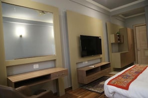Ein Hotelzimmer mit Bett, Fernseher, Schreibtisch und Kleiderschrank.