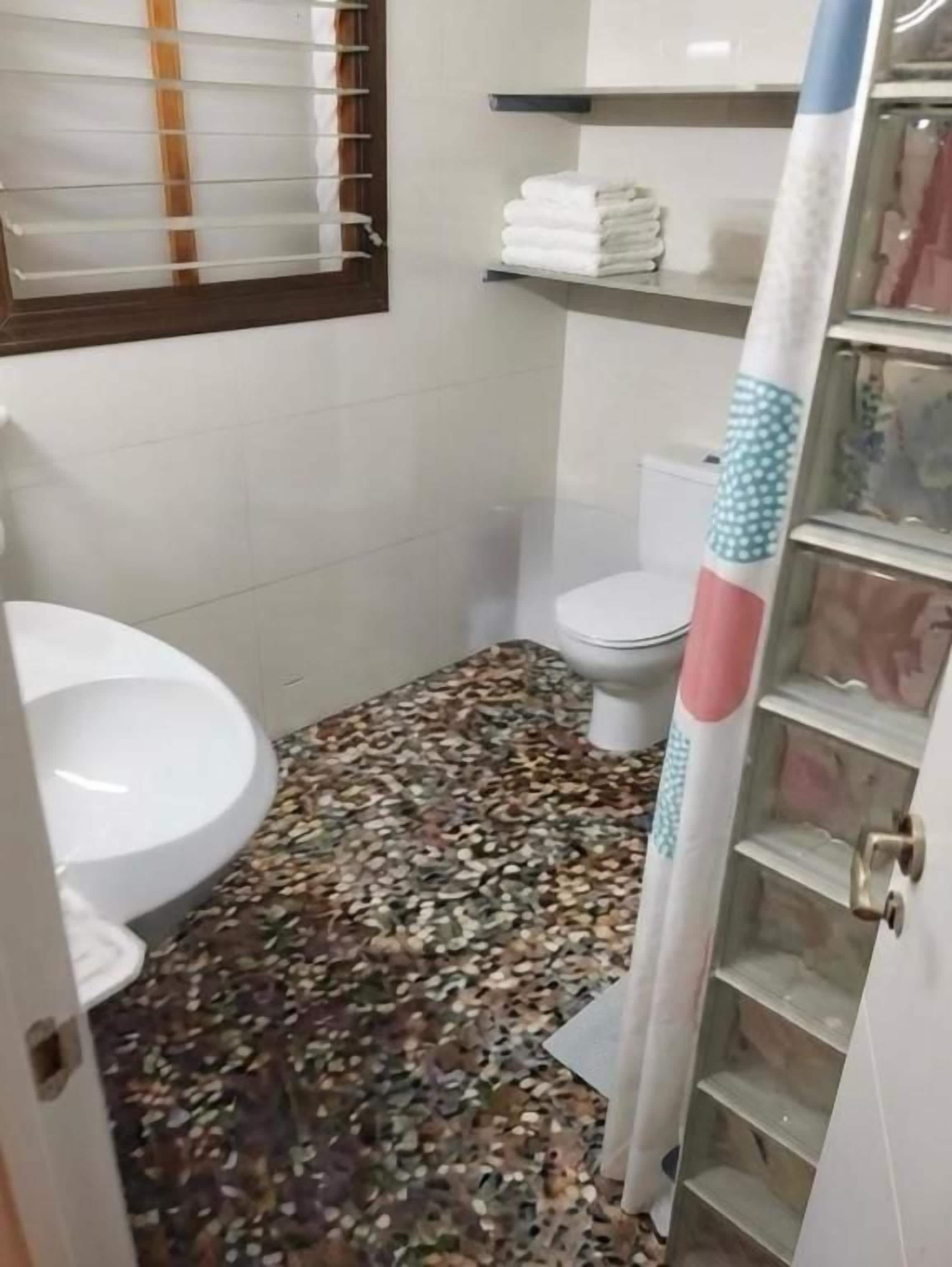 Casa de banho com sanita, lavatório e zona de duche.