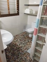 Un baño con inodoro, lavabo y zona de ducha.