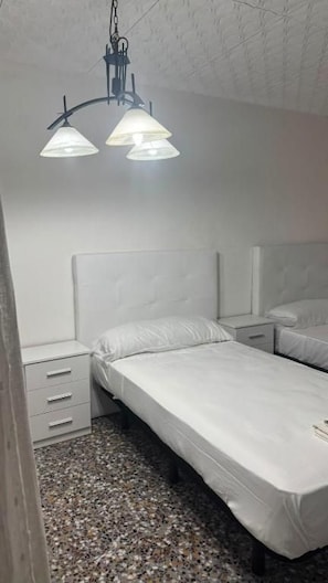 Et soveværelse med en enkeltseng, et sengebord og en hængende lampe.