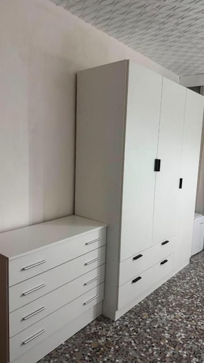 A room with a white wardrobe, a white dresser, and a tiled floor.