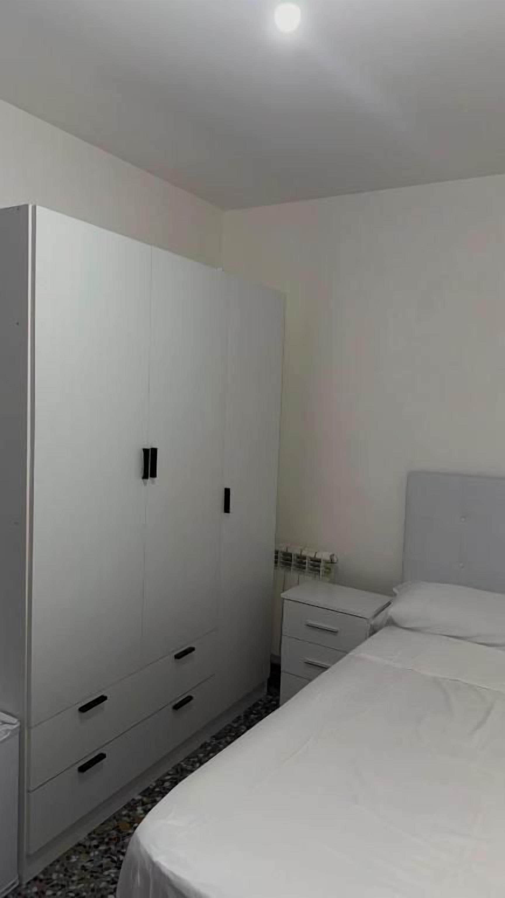 Quarto com cama, guarda-roupa e mesa de cabeceira.