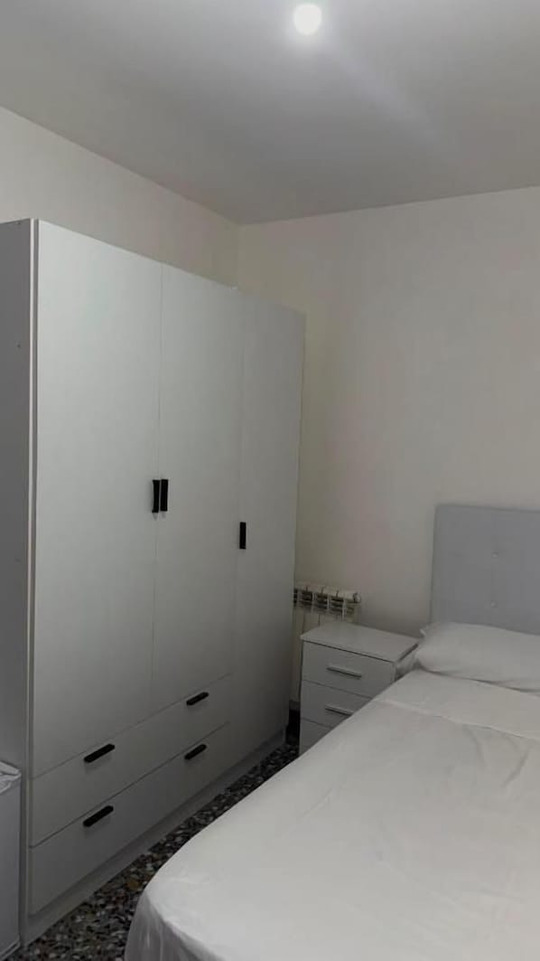 A bedroom with a bed, a wardrobe, and a bedside table.