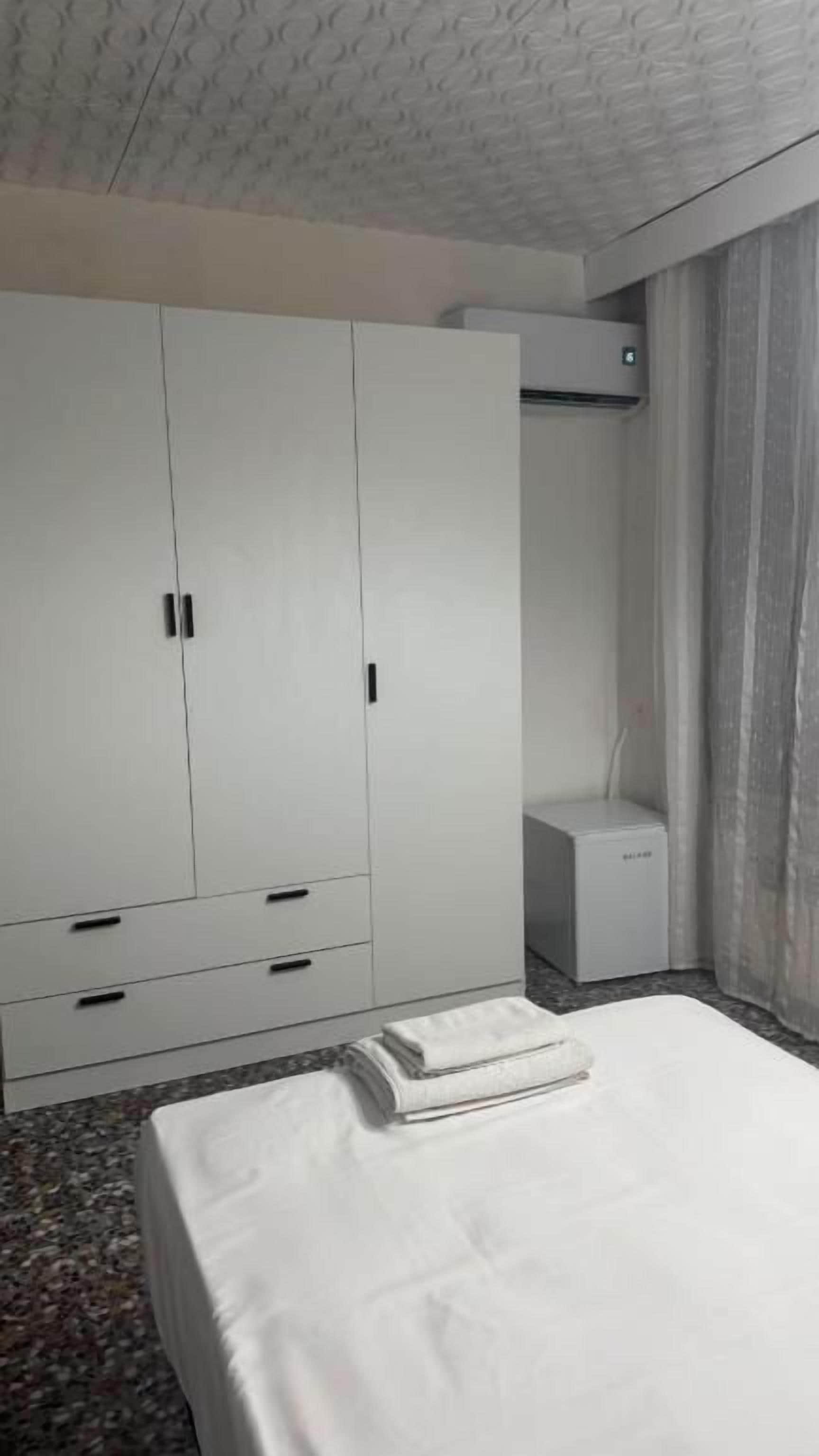 A hotel room with a bed, a wardrobe, and an air conditioning unit.