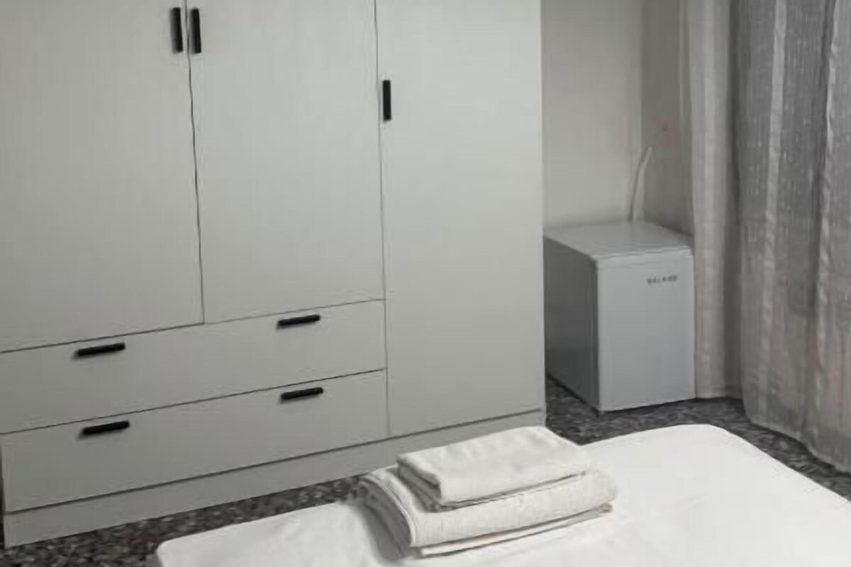Et hotelværelse med en seng, et skab og en aircondition.