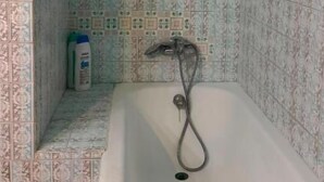 Casa de banho com azulejos estampados, banheira e chuveiro.