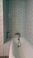 Casa de banho com azulejos estampados, banheira e chuveiro.