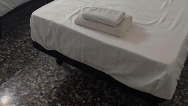 Quarto de hotel com duas camas, cabeceira, mesa de cabeceira e piso de mármore.