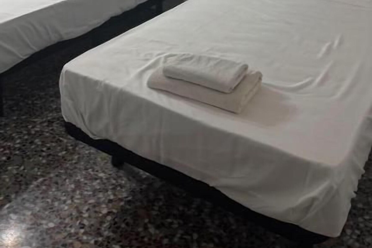 Et hotelværelse med to senge, en sengegavl, et natbord og et marmorgulv.