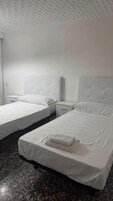 Quarto de hotel com duas camas, cabeceira, mesa de cabeceira e piso de mármore.