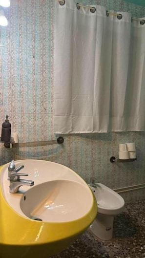 A bathroom with a yellow sink, white toilet, and a shower curtain.