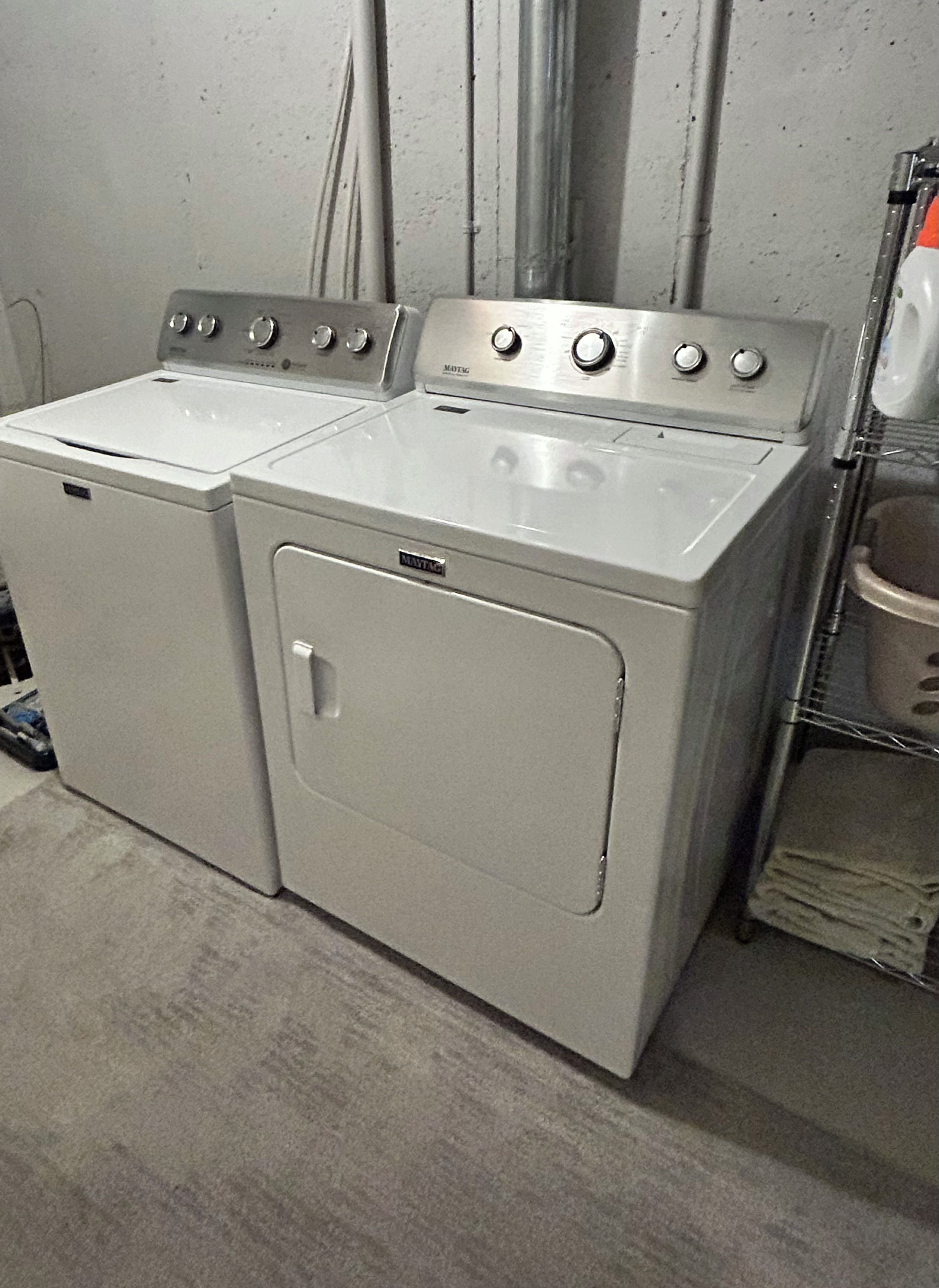 A pair of white front-loading washers in a laundry room.