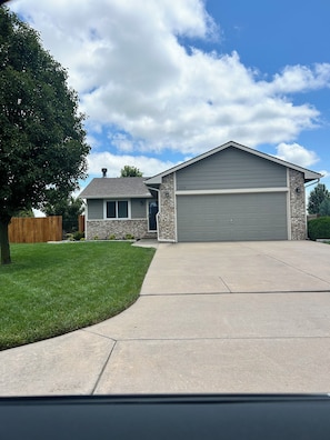 A residential house with a garage, a stone facade, and a well-maintained lawn. - Cozy 3BR Escape in Wichita, Patio & Fire Pit (Wichita)